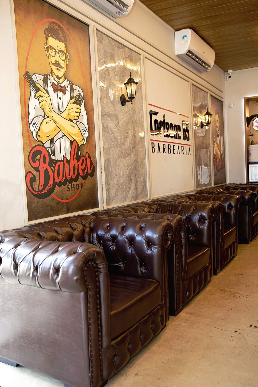 Sala de espera da Corleone 65 com poltronas Chesterfield de couro e o mural Barber Shop